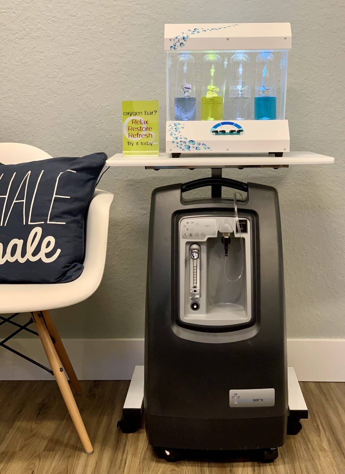 Oxygen bar concentrator and aromatherapy bottles beside a chair with an inhale, exhale pillow