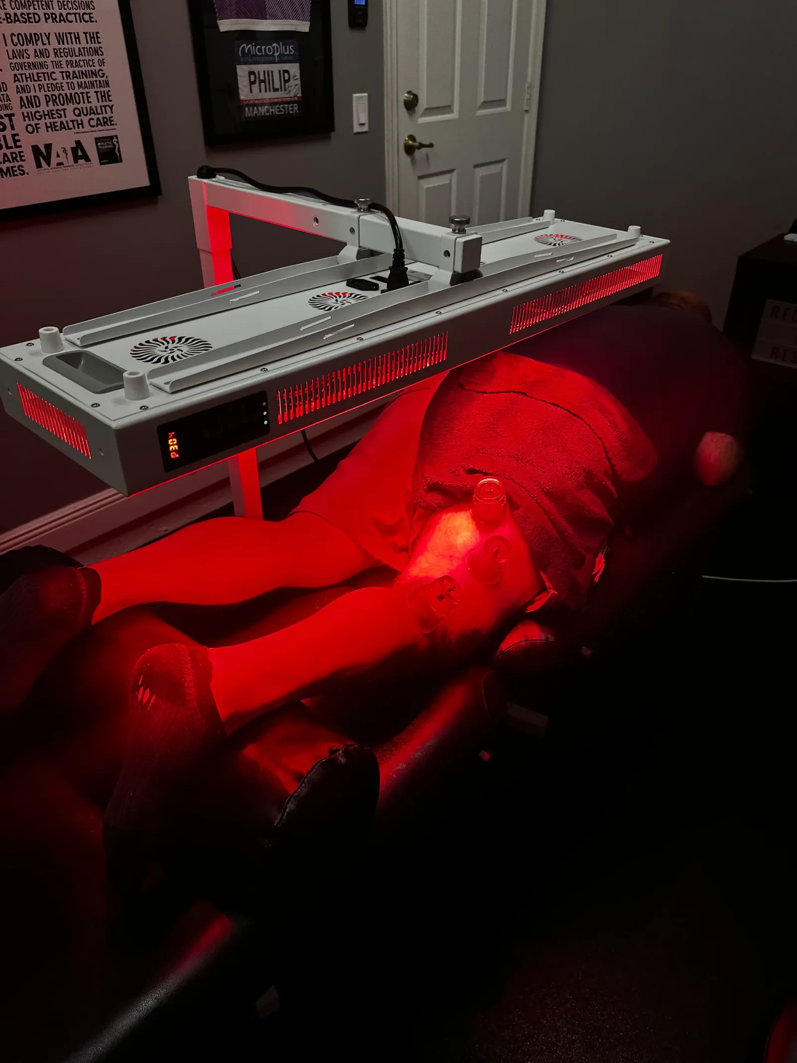 Guest resting on a treatment table beneath a Valo red light panel, legs bathed in red light