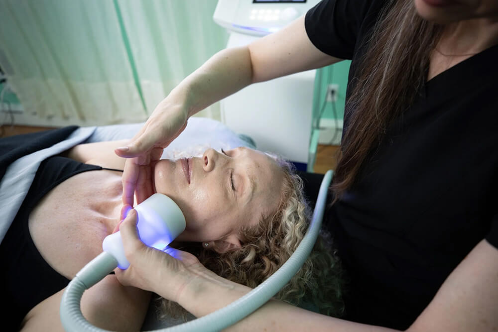 Client relaxing as the CryoSkin wand traces along the jawline during a facial treatment
