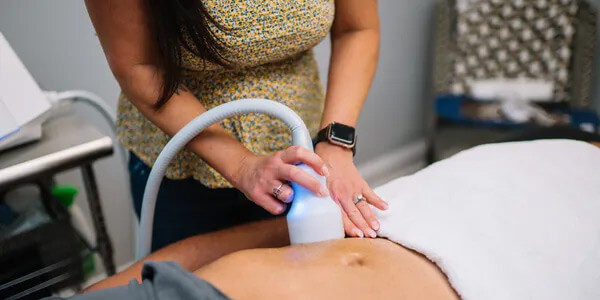Practitioner gliding the CryoSkin wand across a client's stomach during a slimming session